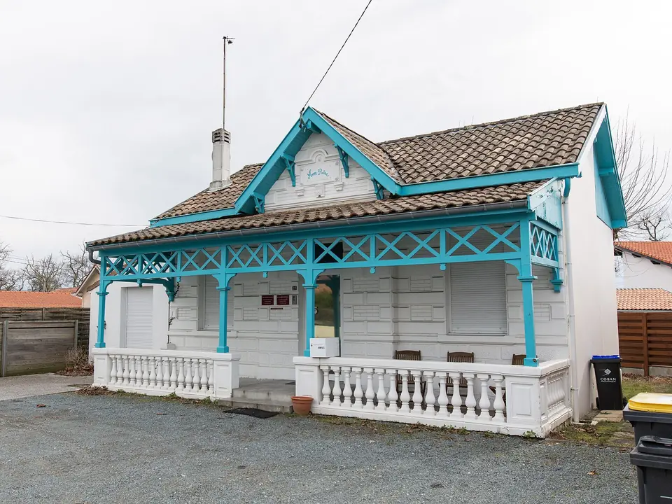 Villa Mon Rêve à Andernos-les-Bains, maison balnéaire en bois peint en blanc et turquoise, avec véranda à balustrade et toit de tuiles.