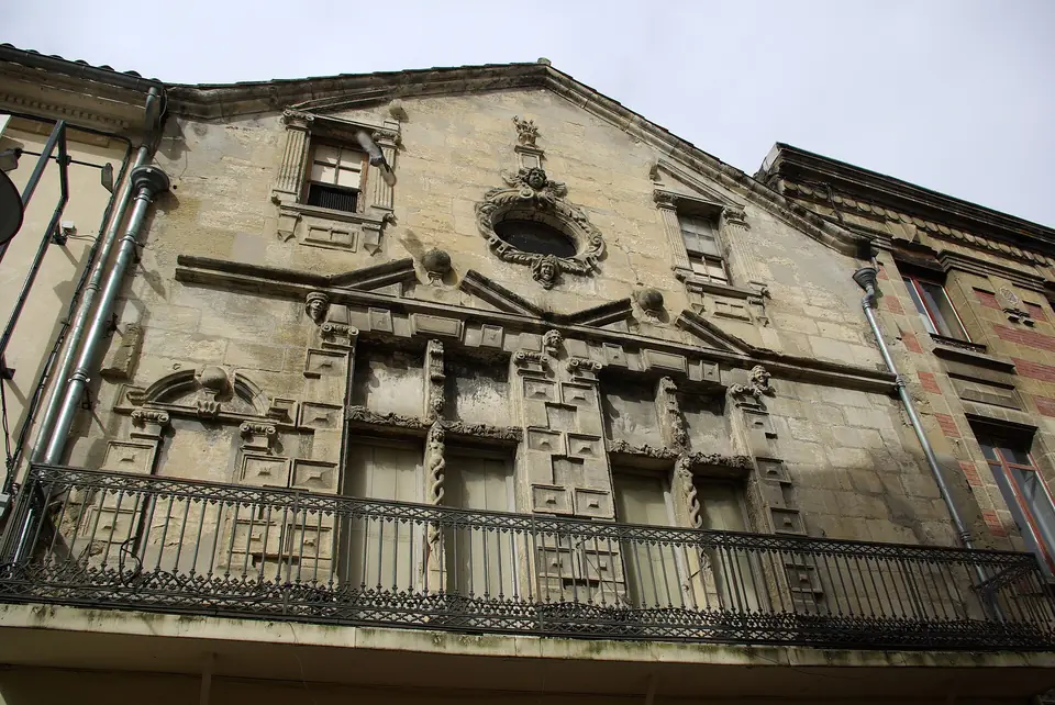 Façade sculptée de la maison du 51 rue Maubec à Langon, en pierre calcaire, avec décor en relief et balcon en fer forgé.